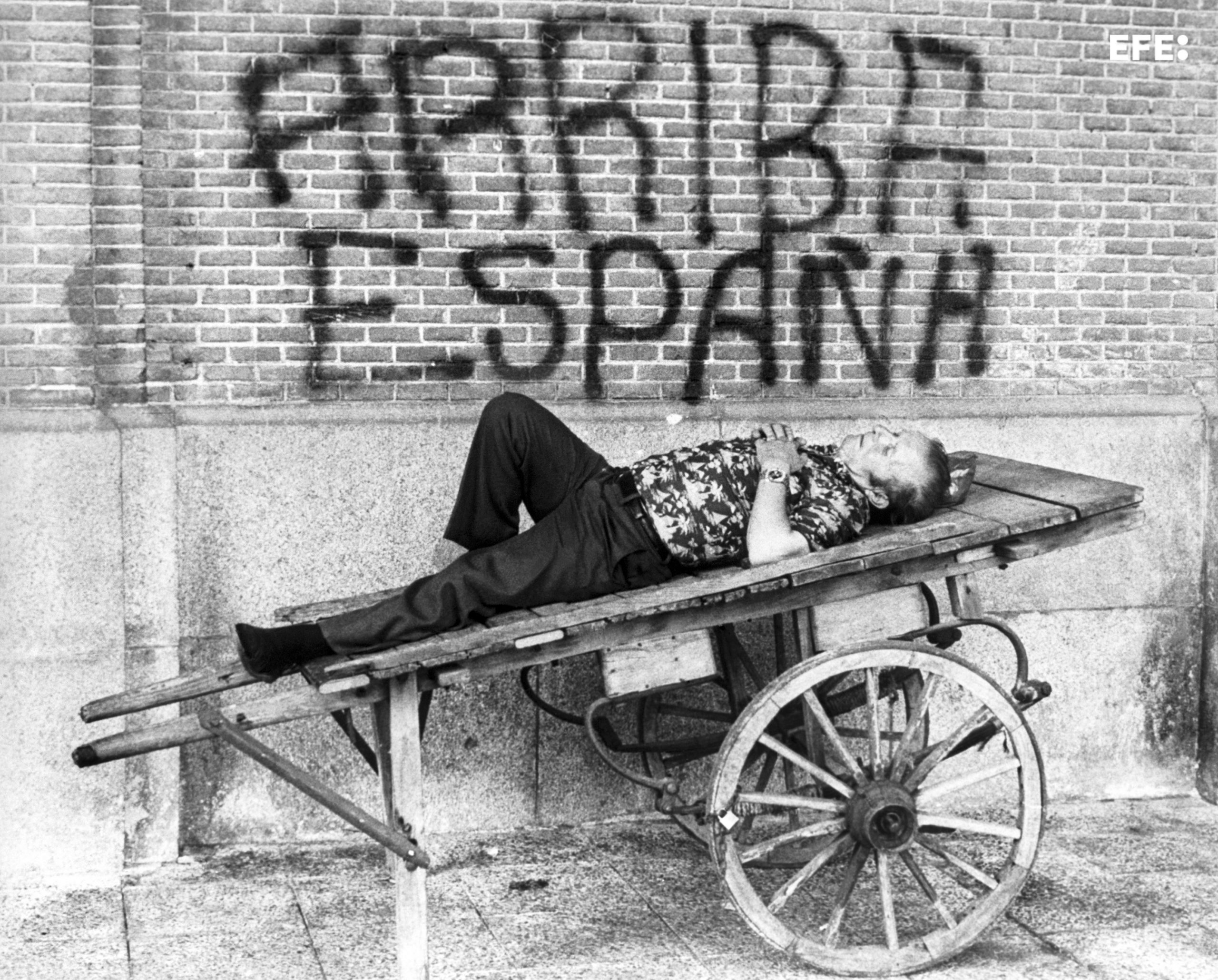 Un hombre descansa en un carro ante una pintada de "Arriba España" EFE/Manuel P. Barriopedro